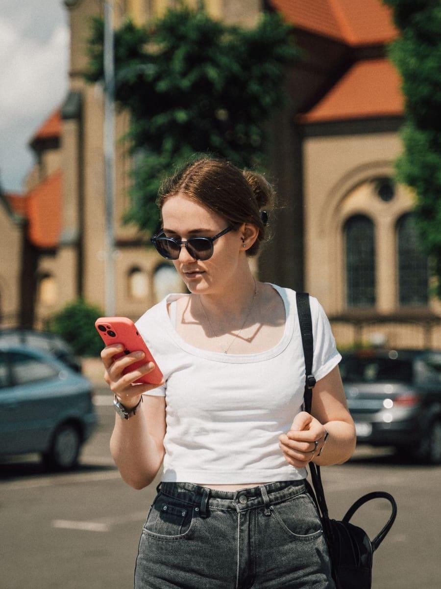 Autobezitter leest een gids op haar telefoon naast haar auto